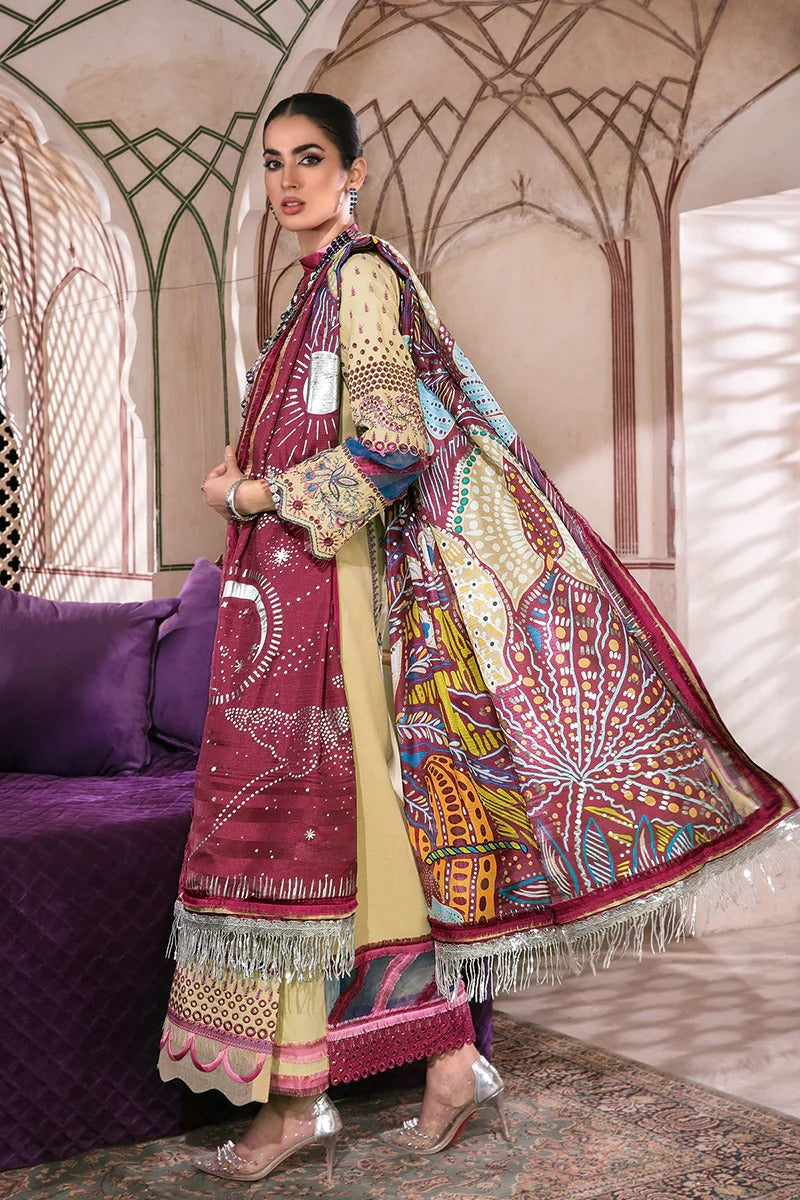A woman models a traditional South Asian outfit featuring a heavily embroidered maroon dupatta, a beige kurta with colorful patterns, and matching trousers, posed in front of an ornate architectural background with a purple sofa.