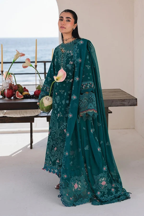 Woman in a teal embroidered outfit holding a flower, with a scenic background.
