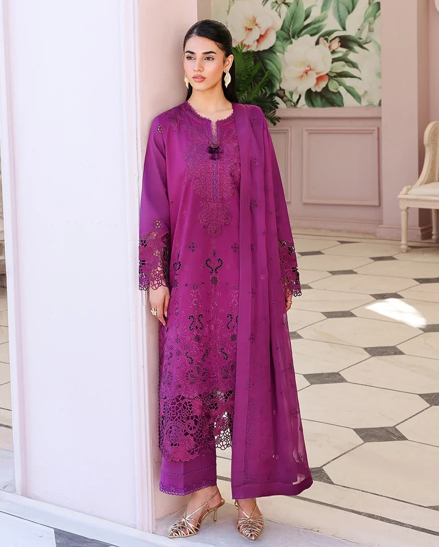 Woman in a purple embroidered outfit standing in a decorated room with floral decorations.