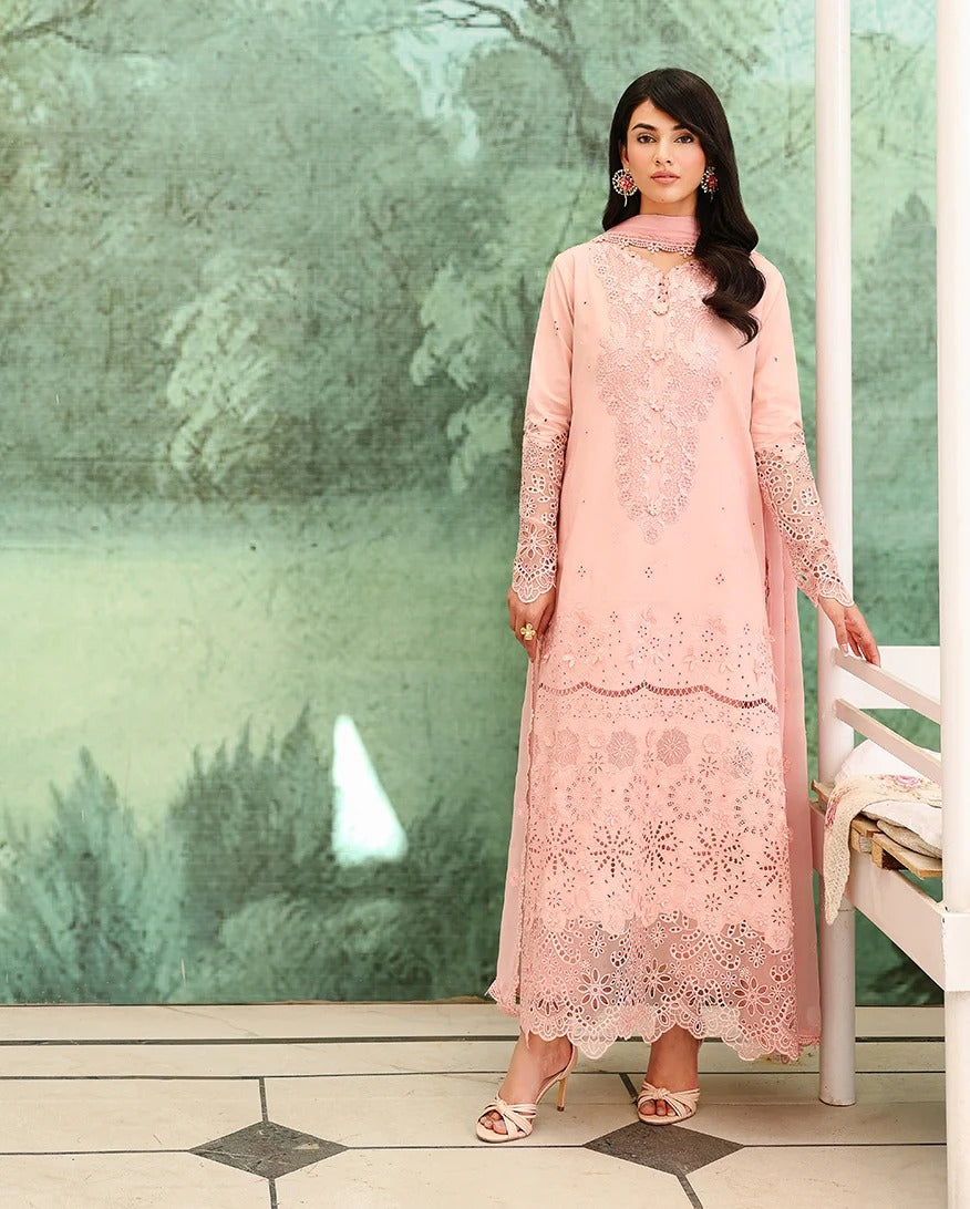 Woman wearing a pink lace dress standing in front of a green floral wall.