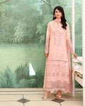 Woman wearing a pink lace dress standing in front of a green floral wall.
