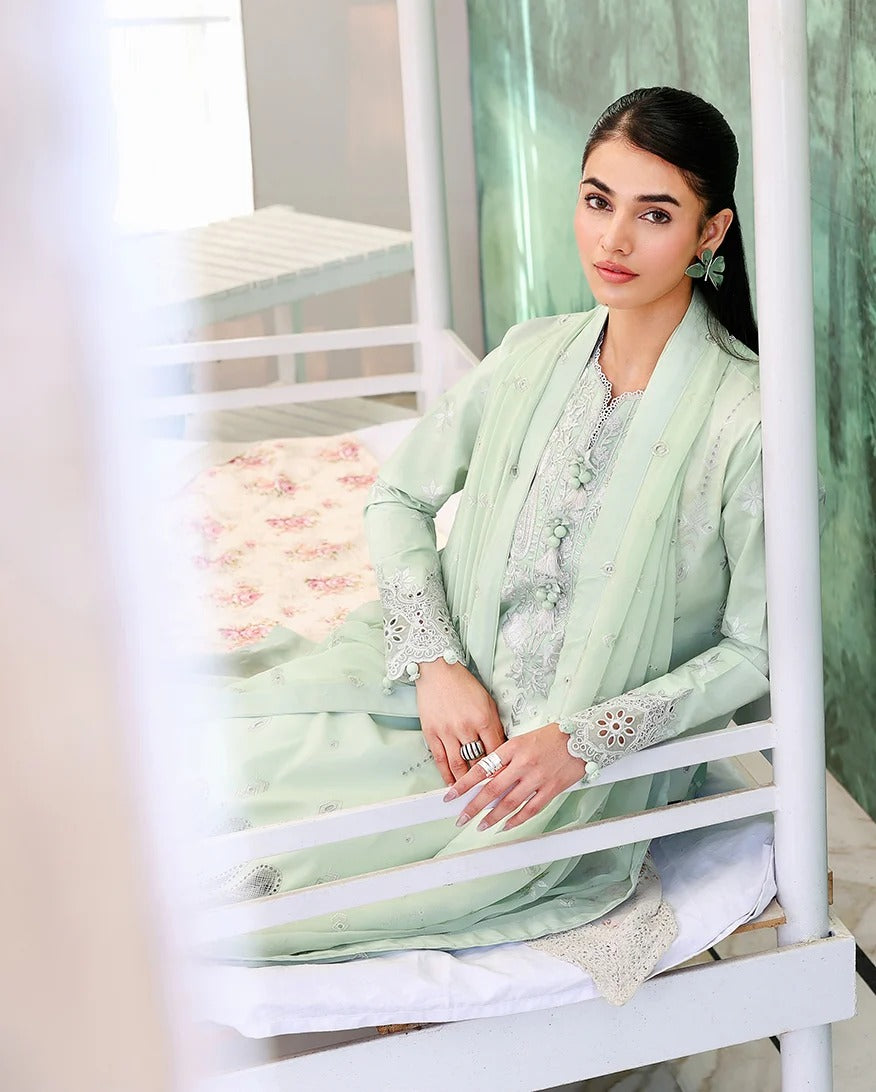 Woman in a light green traditional outfit sitting on a white chair.