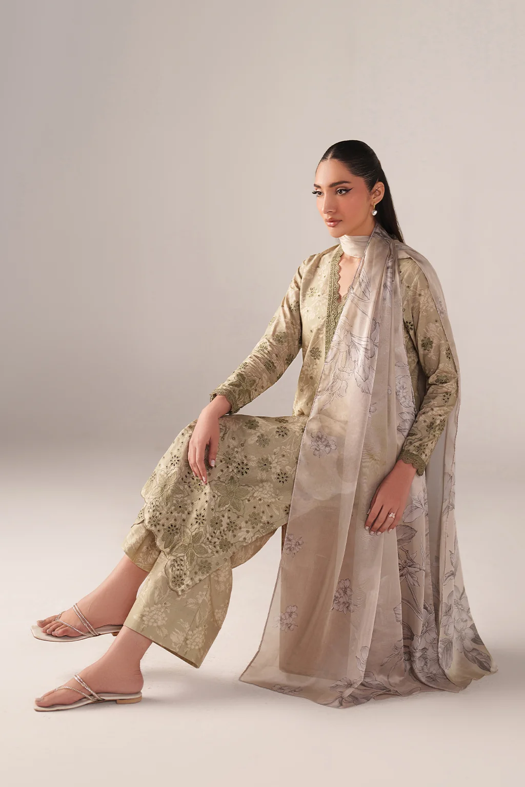 Woman wearing a traditional outfit with a floral pattern on a plain background