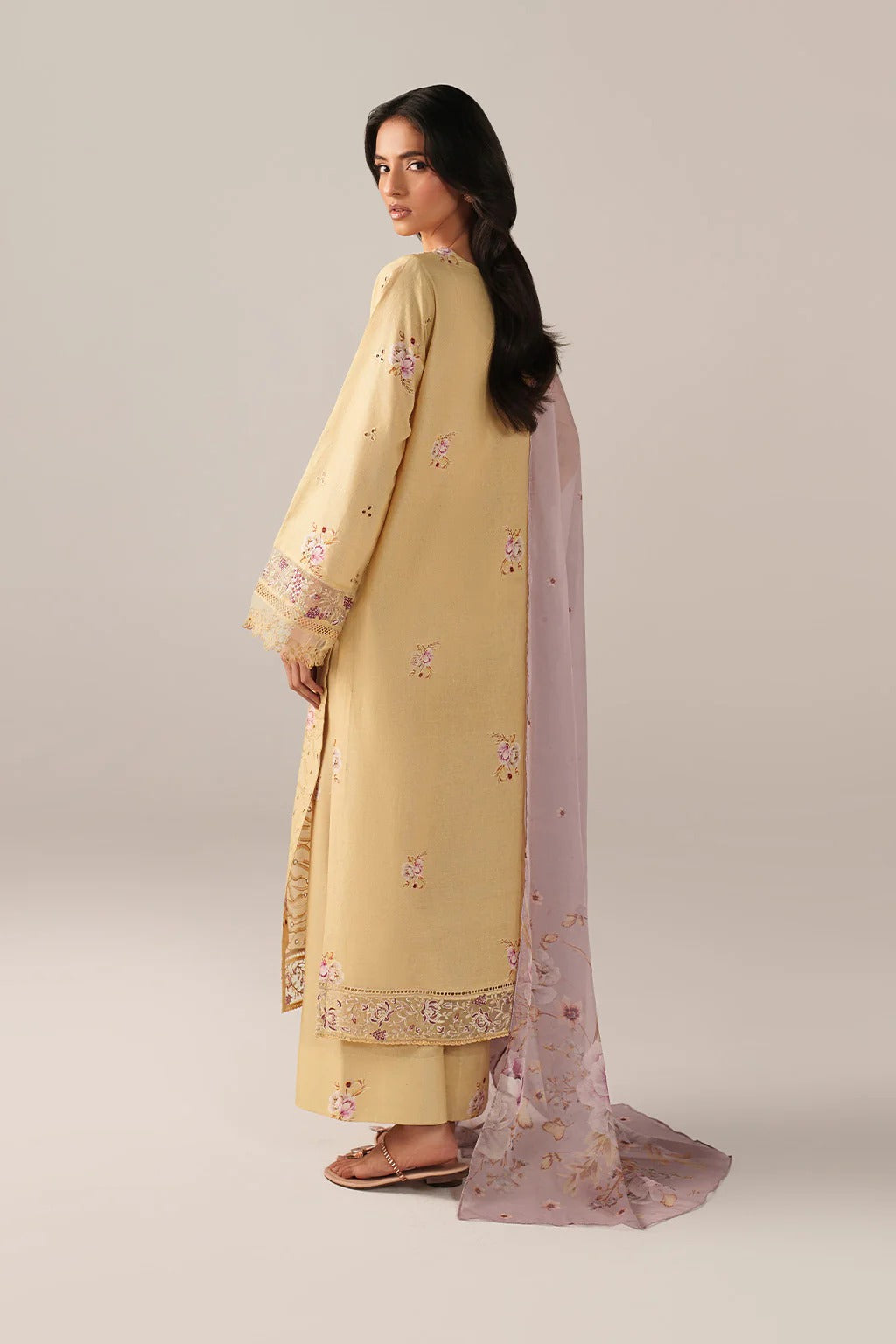 Woman wearing a light yellow embroidered outfit with a matching dupatta on a plain background