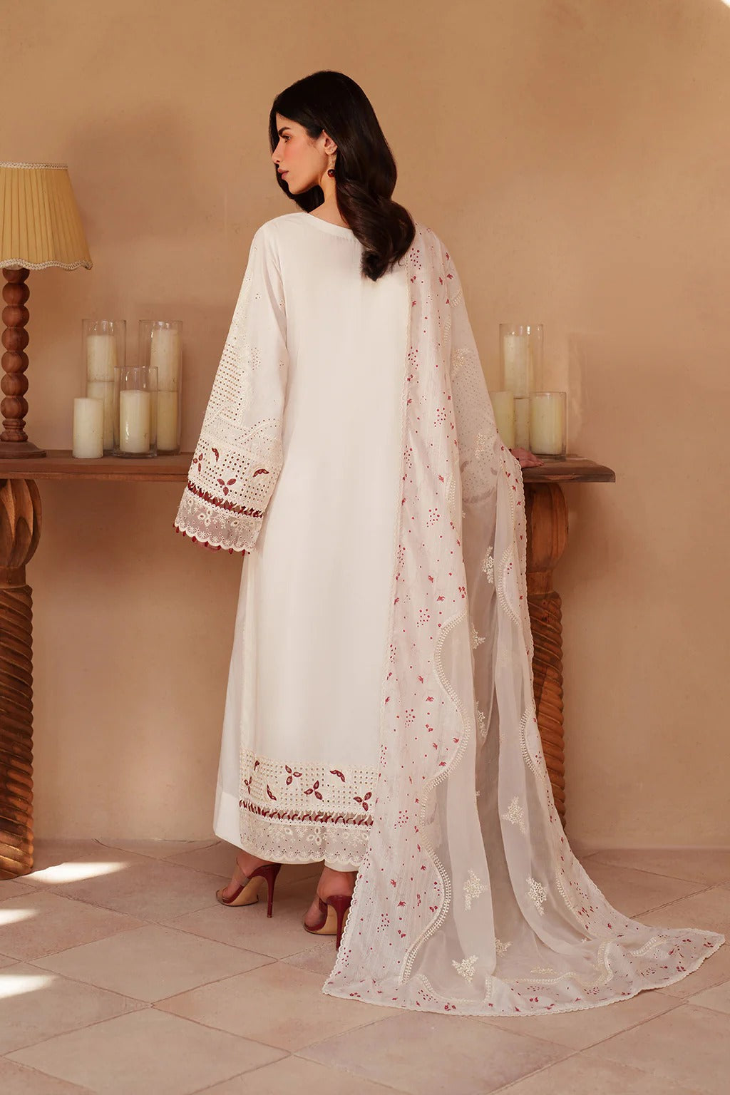 Woman in a white embroidered outfit standing in a room with candles on a table.