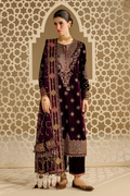A woman models a traditional South Asian outfit consisting of a deep purple velvet kurta with intricate gold and silver embroidery, matching trousers, and a coordinating dupatta, set against a beige geometric patterned wall.