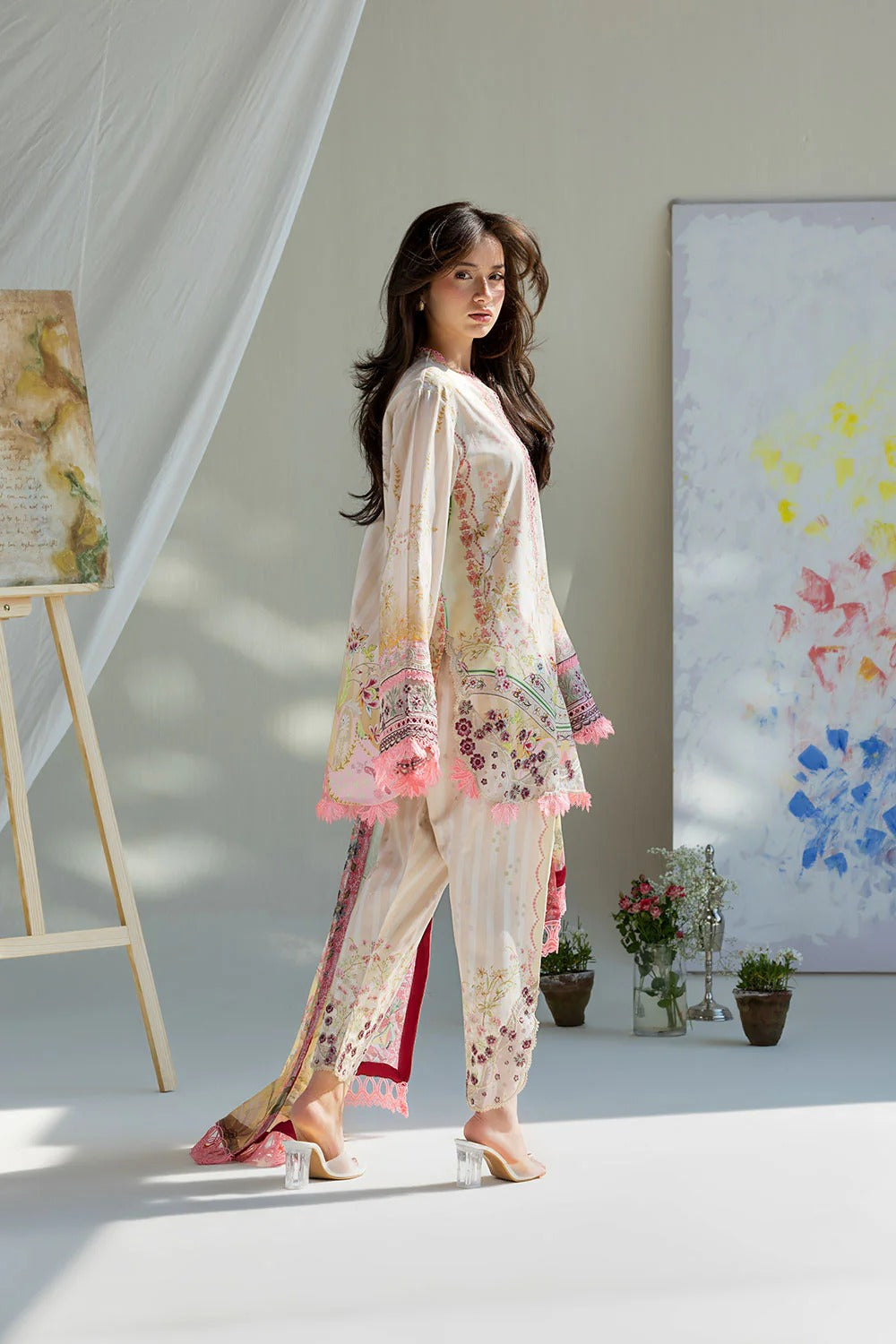 Woman in a floral outfit standing in a room with artistic decorations.