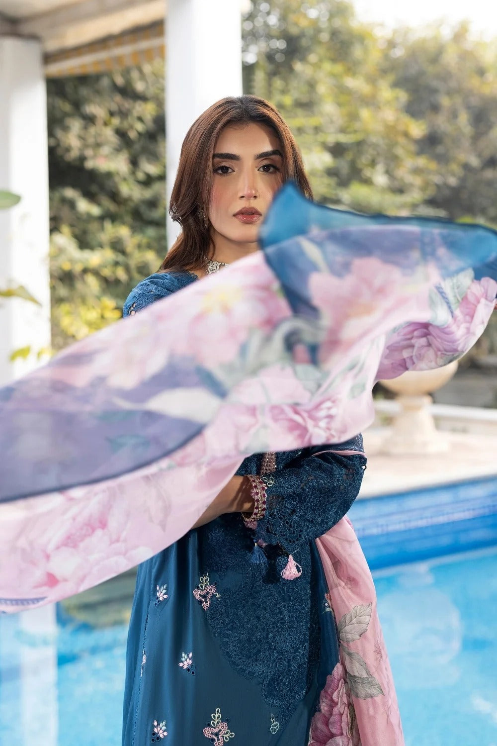 Woman holding a floral scarf by a poolside