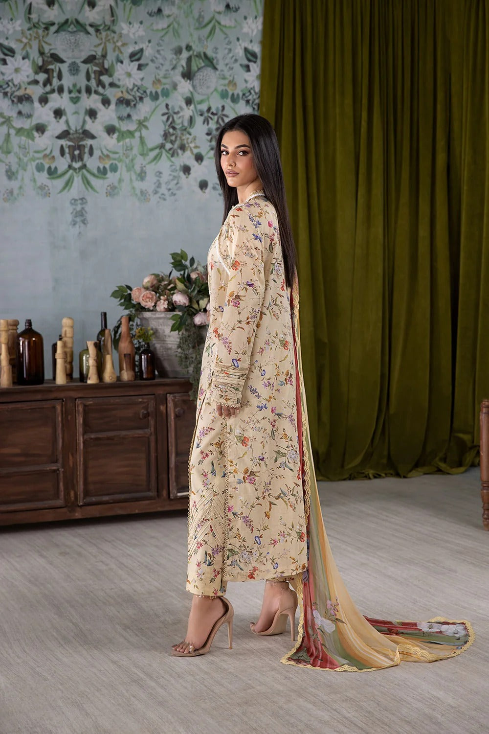 Woman in a floral outfit standing in a room with decorative elements.