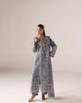 A woman models a traditional long blue embroidered kurta with matching pants and sandals against a plain beige studio background.
