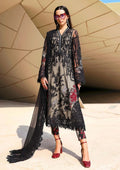 Woman wearing a long, dark floral dress with sheer overlay in front of a modern architectural background.