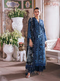 A woman models a traditional blue embroidered salwar kameez set with a matching dupatta in an ornate indoor setting with white planters and a bench.