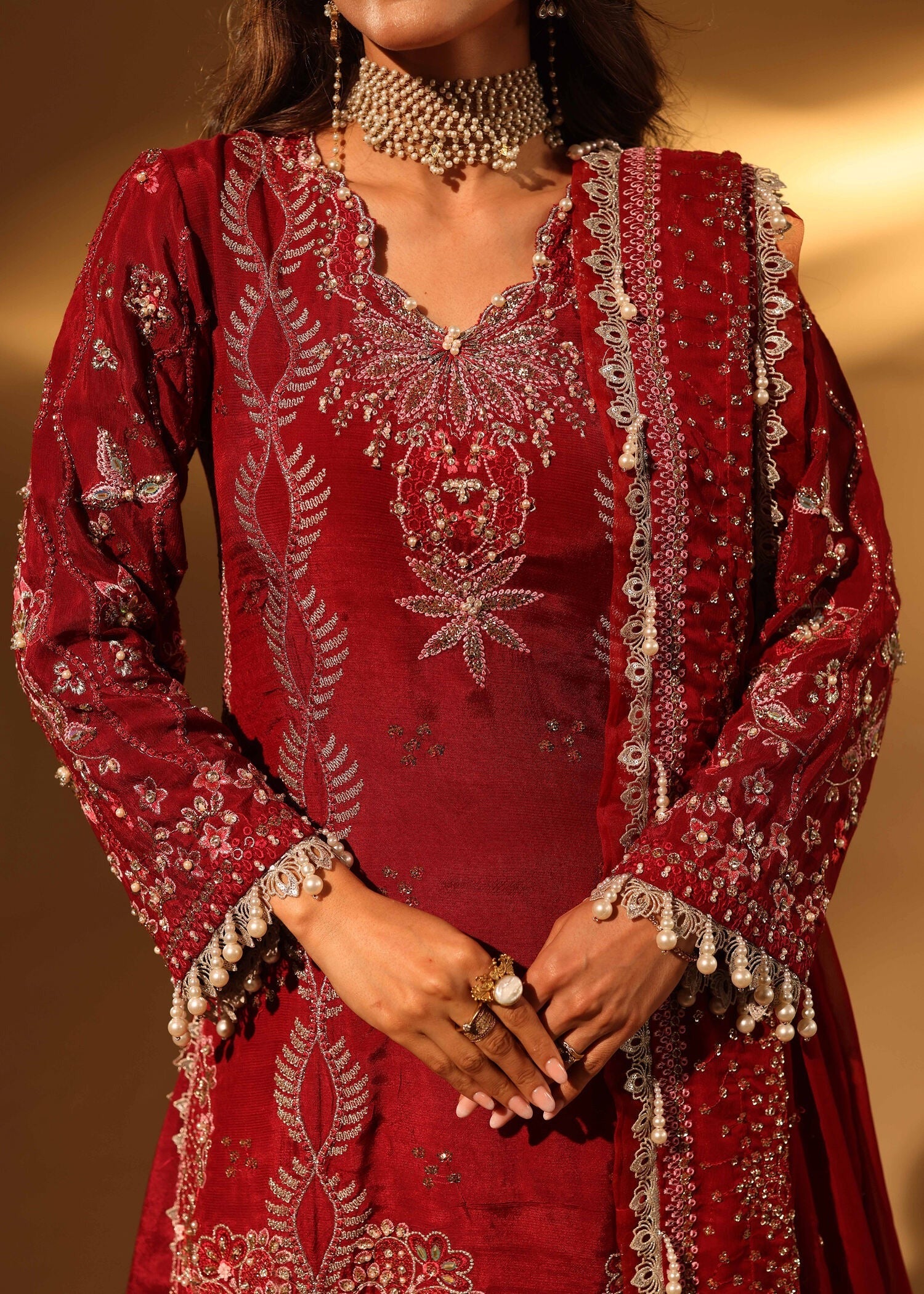 Red embroidered traditional outfit with intricate patterns on a plain background