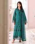 Woman wearing a teal embroidered dress in a decorated room.