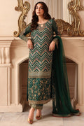 A woman models a traditional Indian ethnic outfit consisting of a deep green kurta with intricate gold and beige embroidery, matching trousers, and a sheer green dupatta, posed in front of a classical fireplace.