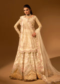 Woman wearing a traditional embroidered outfit with a sheer dupatta against a brown background