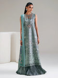Woman wearing a long, embroidered dress with a matching scarf on a neutral background