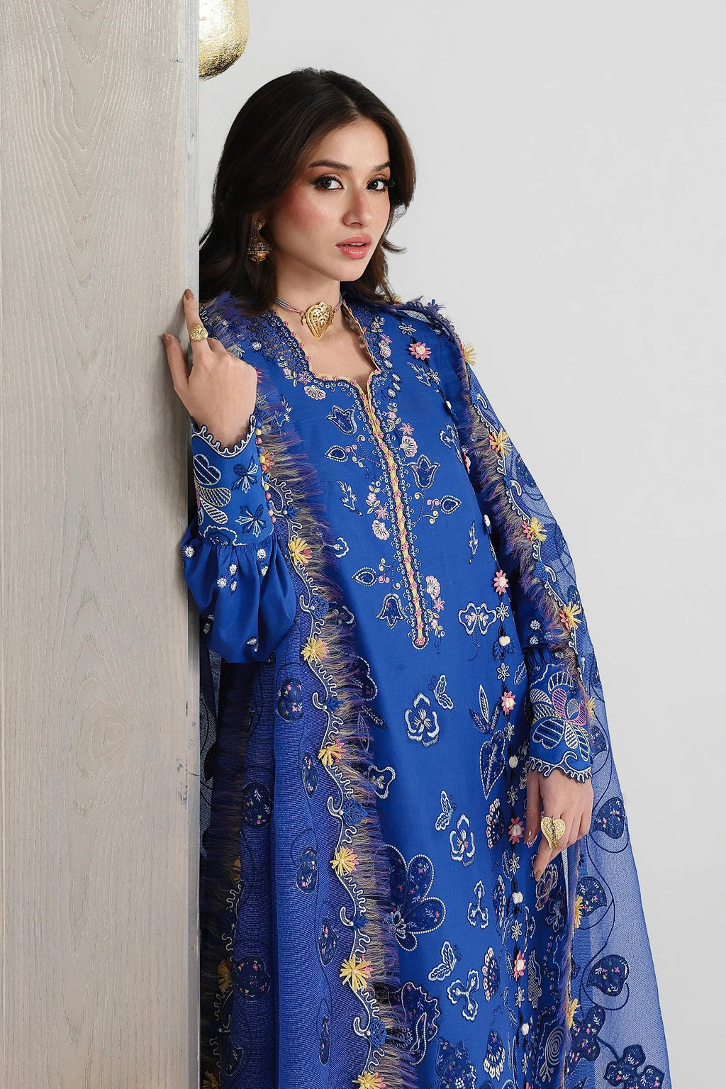 Woman wearing a blue embroidered dress against a neutral background