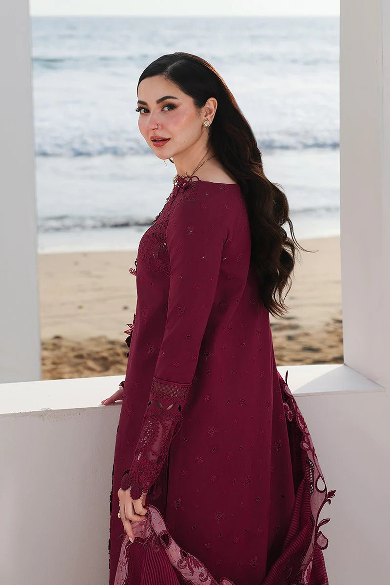 Woman in a burgundy dress standing by a window with a beach view.