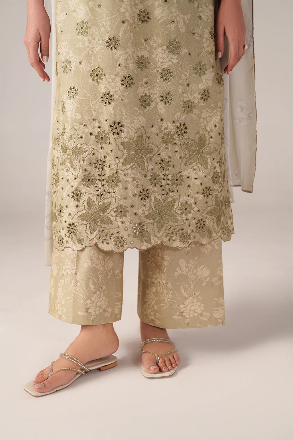 Person wearing a beige floral lace outfit on a plain background