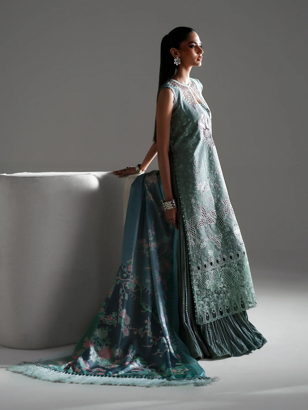 Woman in a traditional outfit with a floral shawl against a gray background