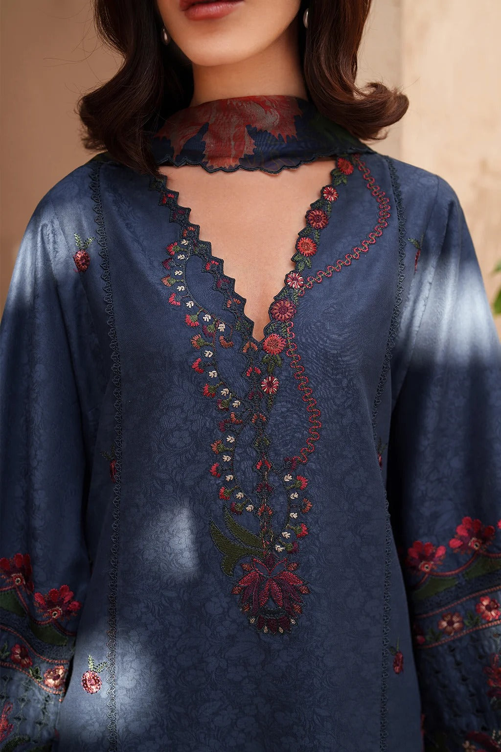 Blue embroidered garment with intricate designs on a neutral background