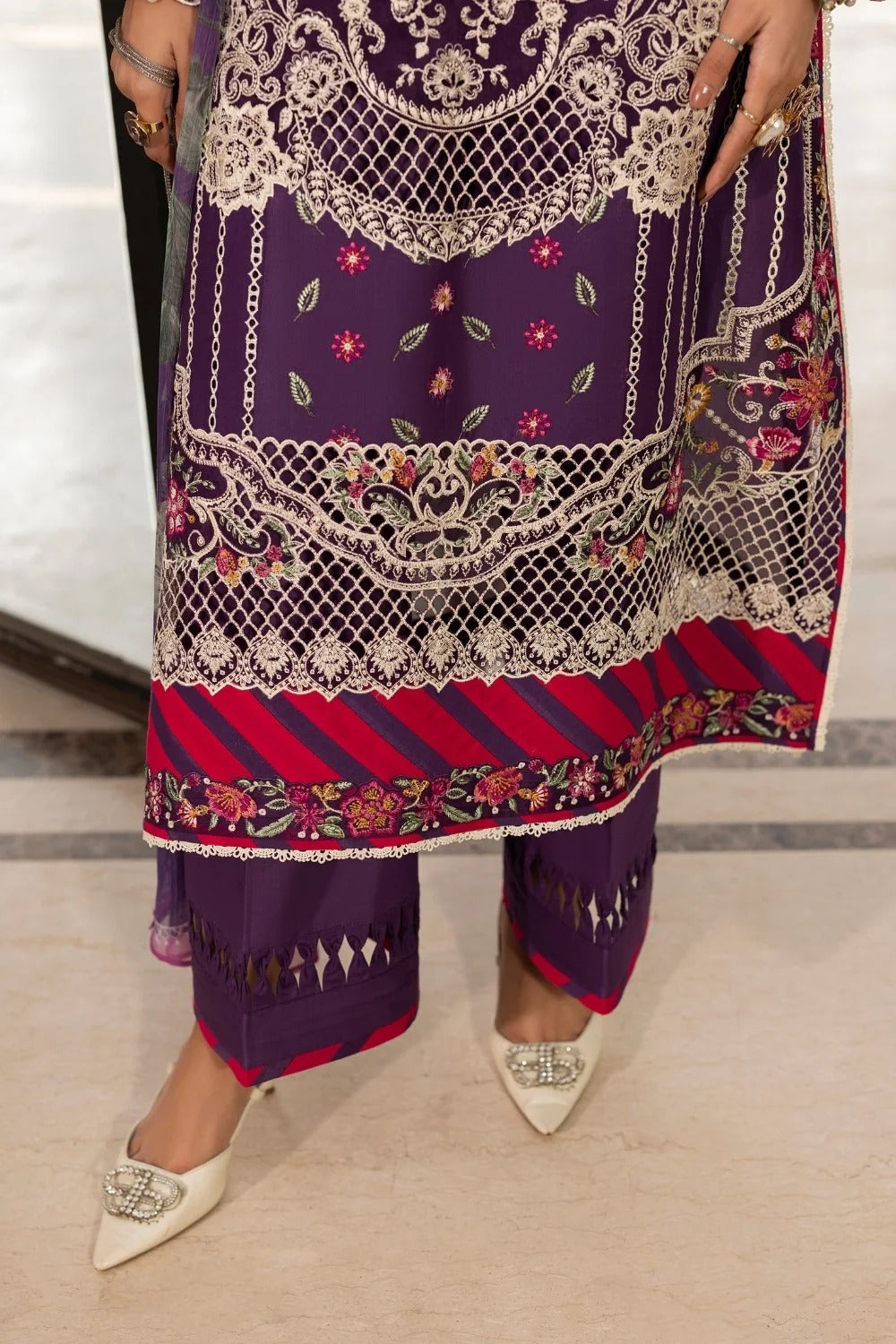 Purple embroidered outfit with red accents on a neutral background