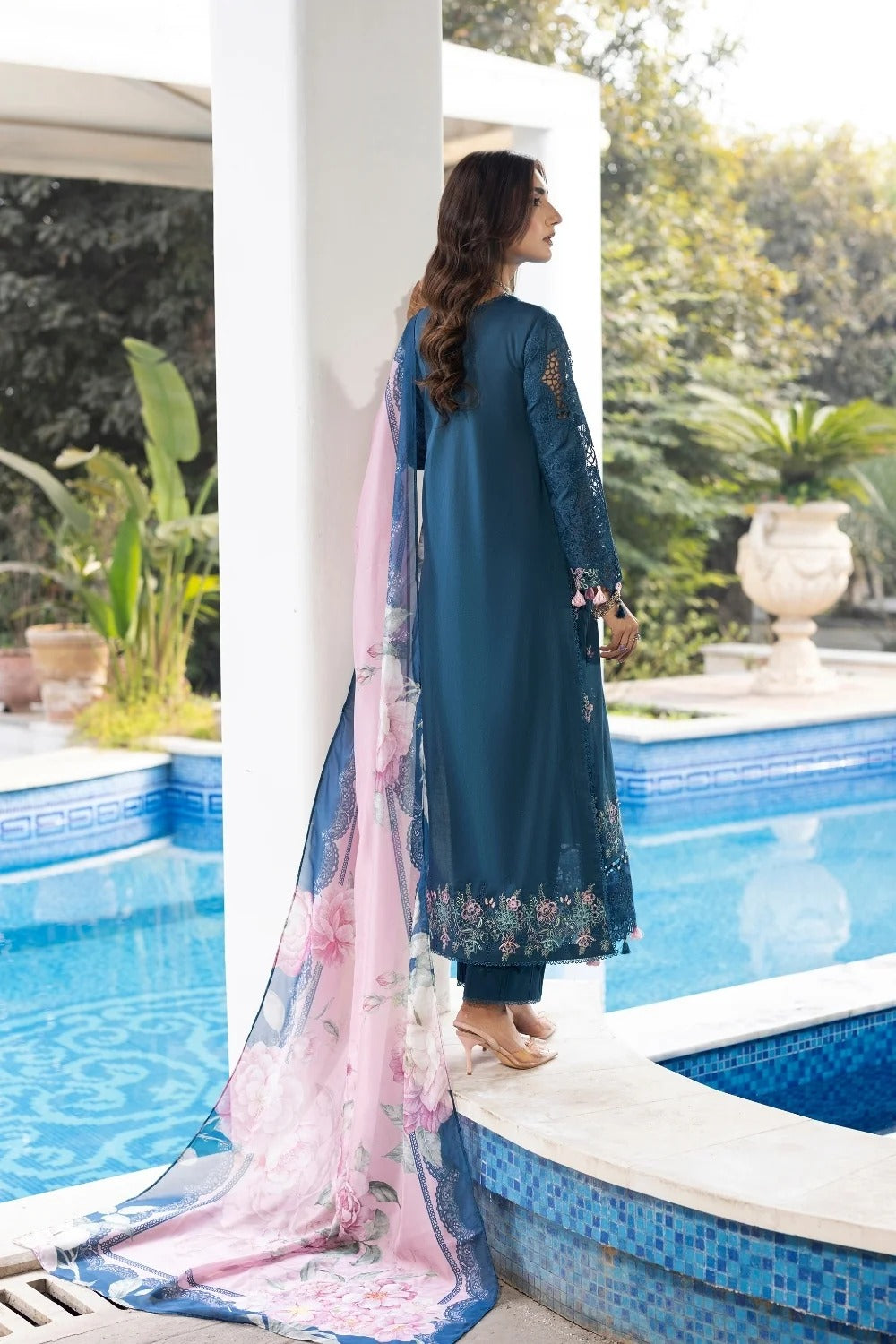 Woman in a blue traditional outfit with a pink dupatta by a poolside