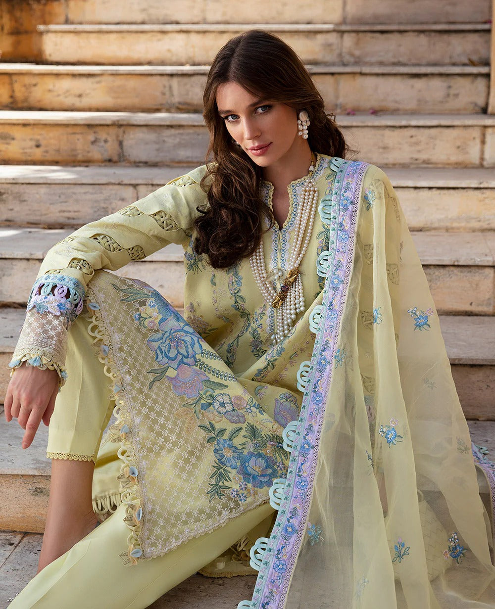 Woman in a light green embroidered traditional outfit sitting on wooden steps.