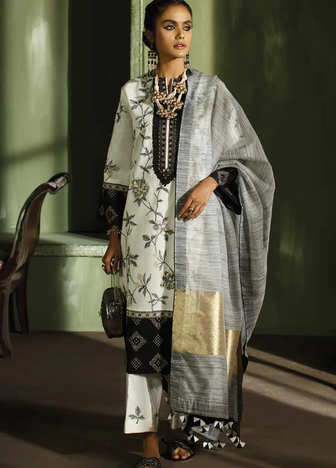 Woman wearing a traditional outfit with a black and white patterned dress and a light gray dupatta.