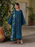 Woman wearing a blue embroidered dress standing outdoors with plants in the background
