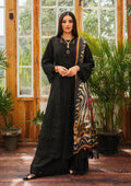 A woman modeling a black embroidered kurta set with a patterned dupatta in a rustic indoor setting with wooden doors and potted plants.