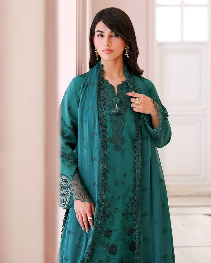 Woman wearing a teal embroidered outfit with a neutral background