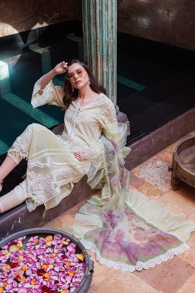 Woman in a flowing dress sitting by a pool with petals.