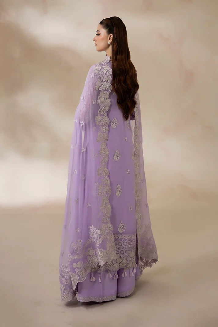 A woman shown from the back wearing a lavender purple traditional outfit with intricate silver embroidery and a matching sheer outer layer, set against a soft beige studio backdrop.