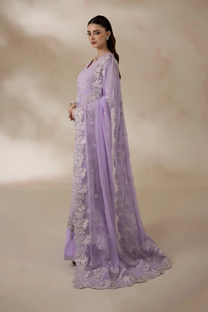 A woman modeling a lavender purple traditional gown with intricate white floral embroidery, set against a warm beige studio backdrop.