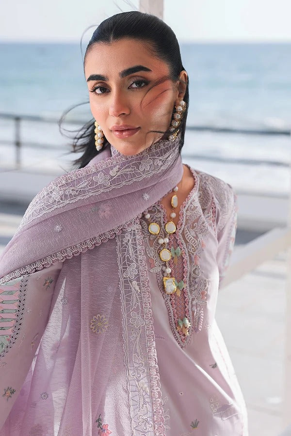 Woman wearing a light purple embroidered dupatta with a blurred ocean background