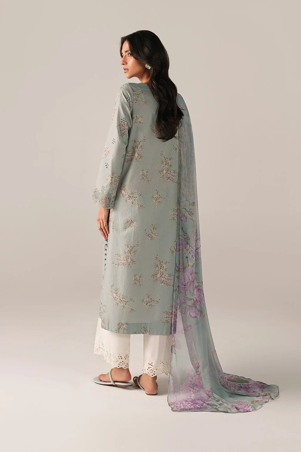 Woman wearing a light green embroidered outfit with a purple dupatta on a plain background