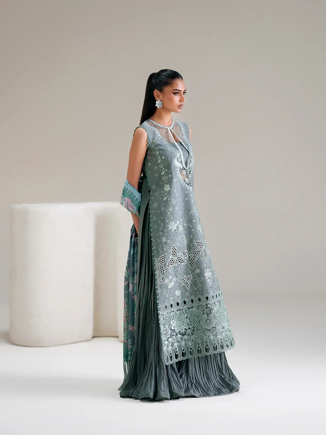 Woman wearing a long, elegant dress with intricate patterns on a plain background