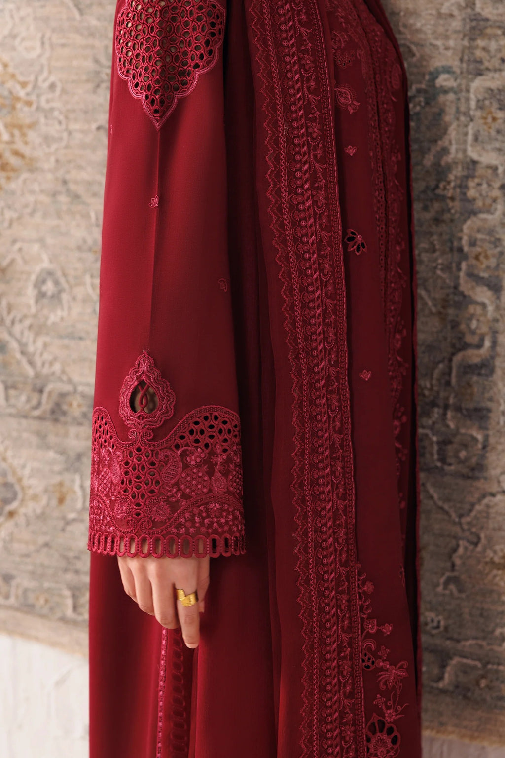 A close-up of a deep red embroidered abaya with matching sheer dupatta, featuring intricate lace and floral embroidery on the sleeve cuffs and front panel, worn by a model with a gold ring.