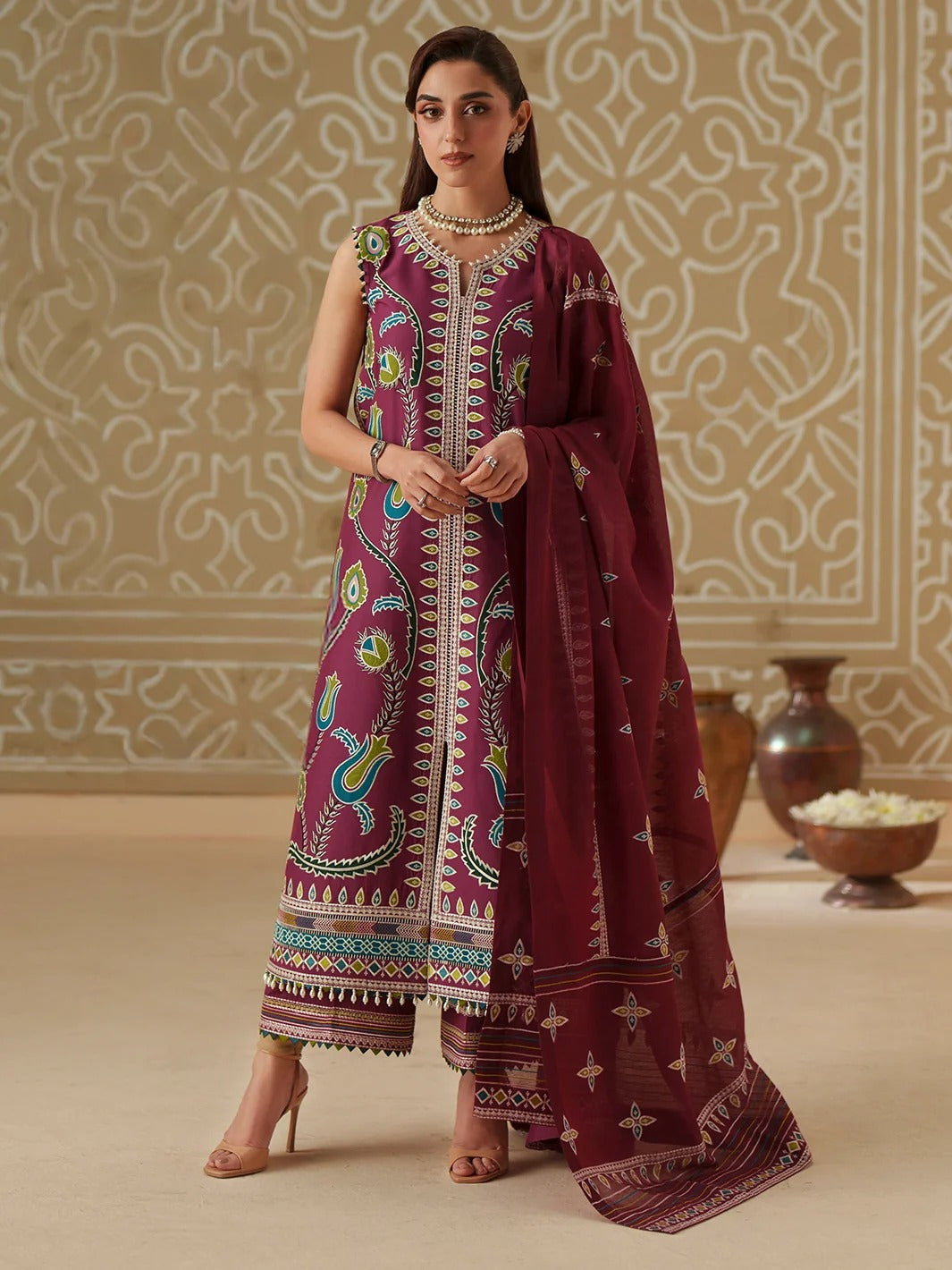 Woman wearing a traditional embroidered outfit in a decorated room.