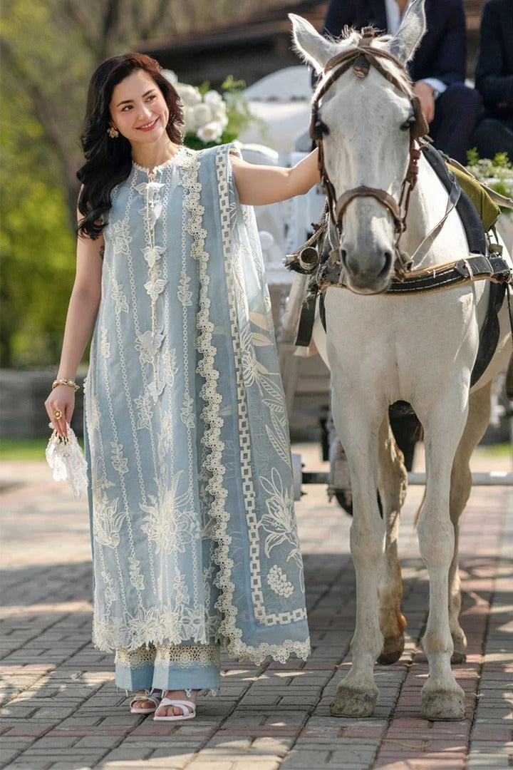 Woman in a light blue traditional outfit standing next to a white horse on a paved path.