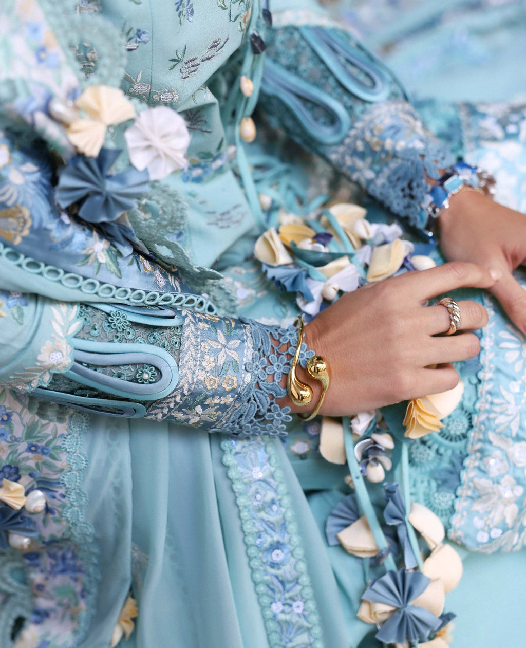Close-up of a person wearing a detailed blue embroidered garment with floral patterns.