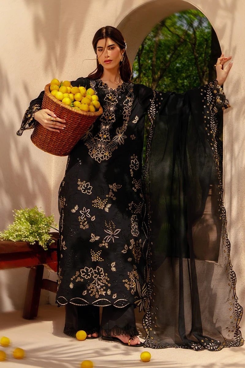 Woman in a black embroidered dress holding a basket of lemons in a decorative setting.