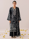 A woman modeling a black embroidered kurta with white floral patterns, paired with black pants, standing against a light beige background with scattered yellow lemons on the floor.