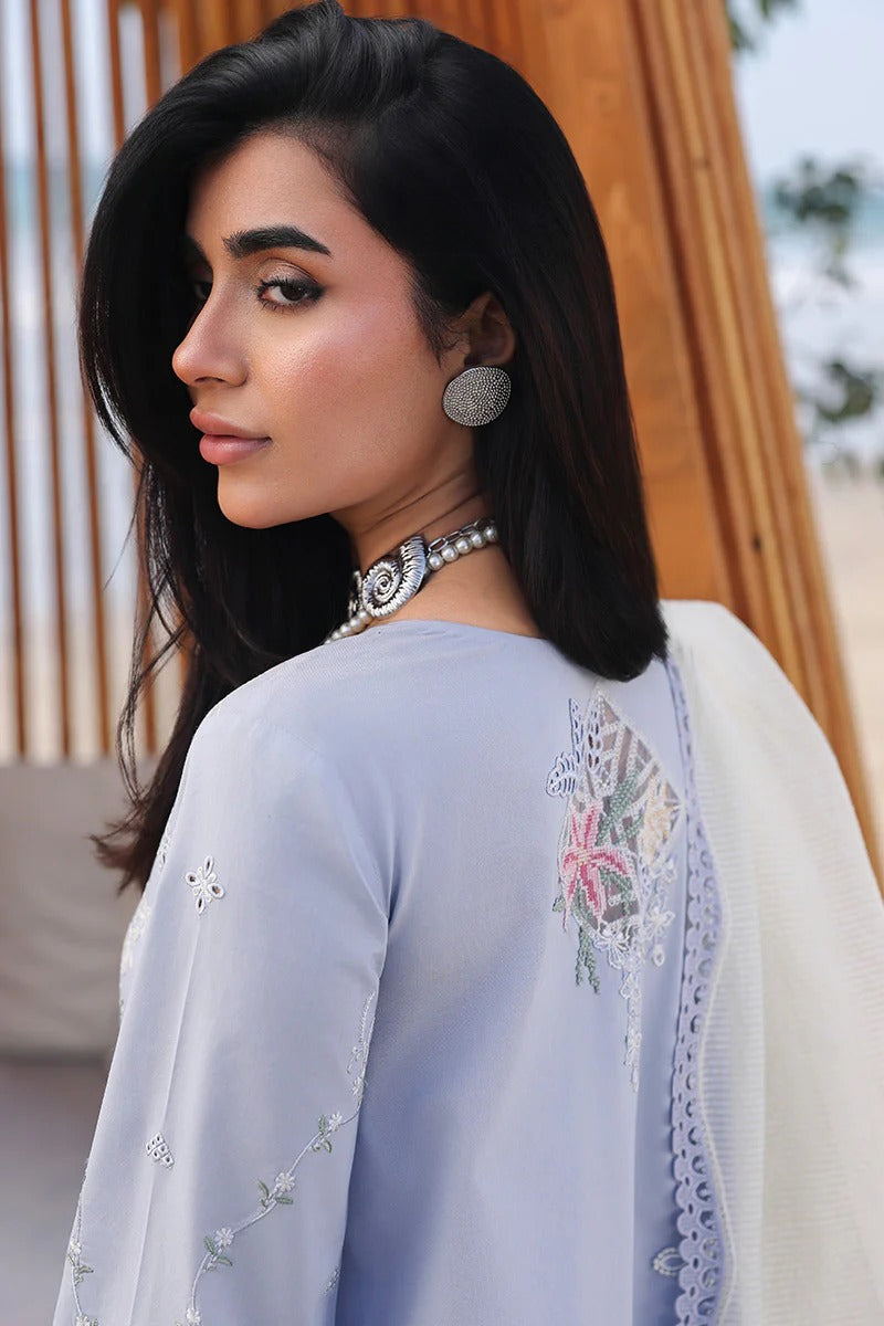 Woman wearing a light blue embroidered outfit with a white dupatta.