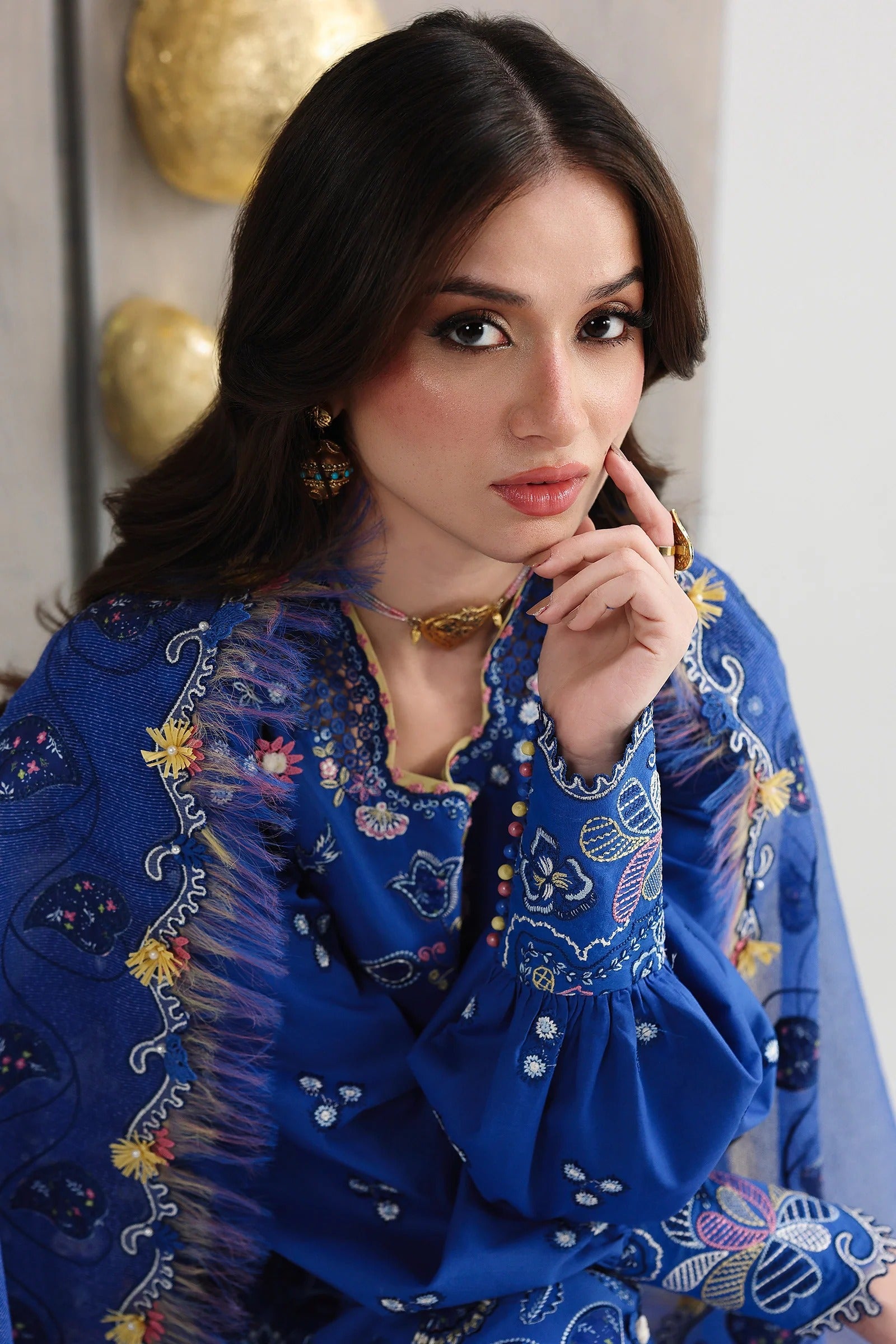 Woman wearing a blue embroidered traditional outfit with a white background