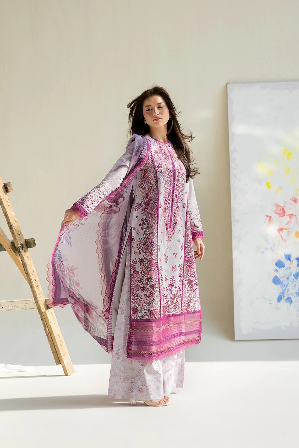 Woman wearing a white and pink traditional outfit in a minimalistic setting.