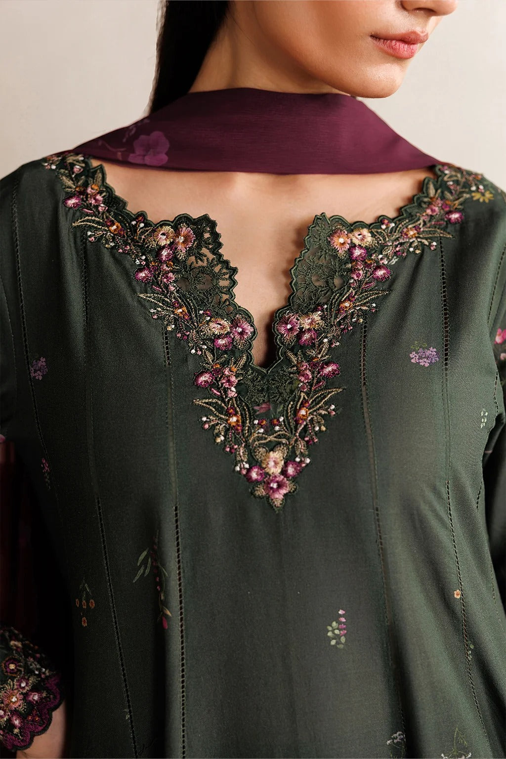 Close-up of a dark green embroidered garment with intricate patterns.