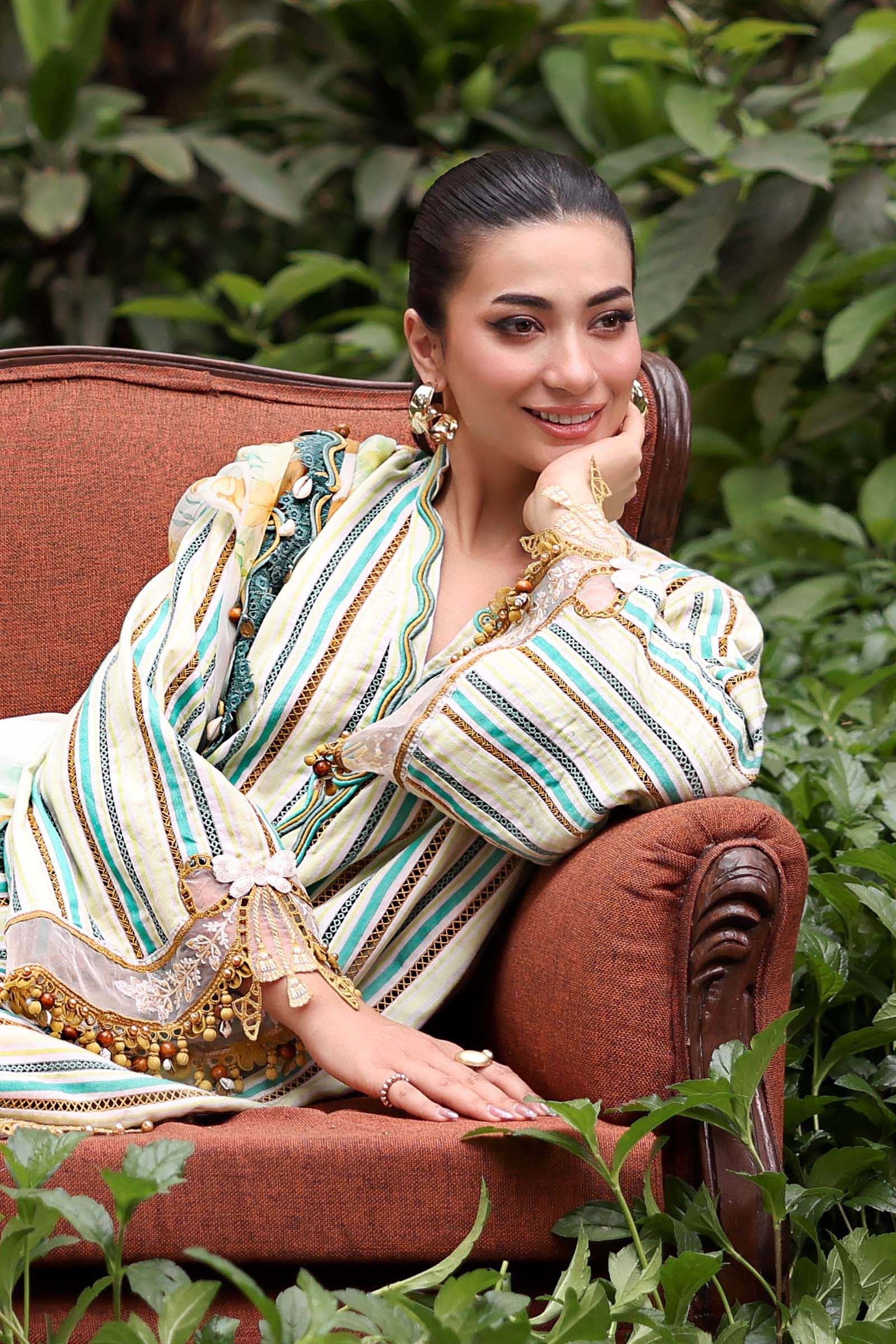 Woman in traditional attire sitting on a red chair with greenery around